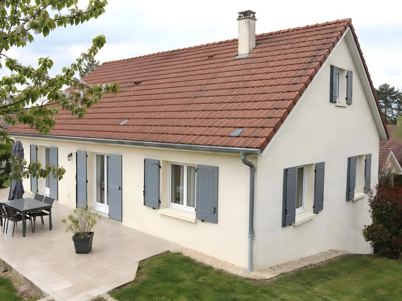 Le même pavillon, tuiles démoussées et propres, gouttière dégagée, terrasse nette au pied.