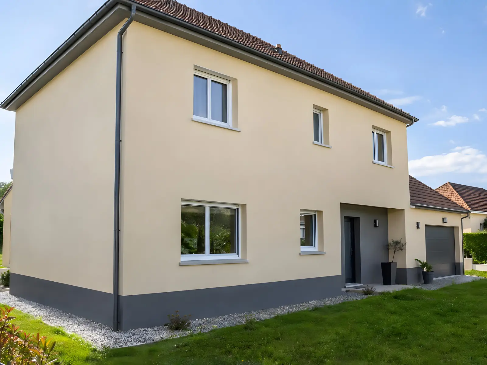Maison à étage à l’enduit beige neuf, soubassement gris anthracite et allée de gravier