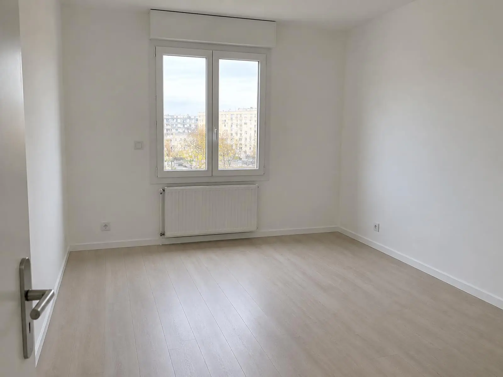 La même pièce aux murs et au plafond d’un blanc mat égal, radiateur blanc sous la fenêtre