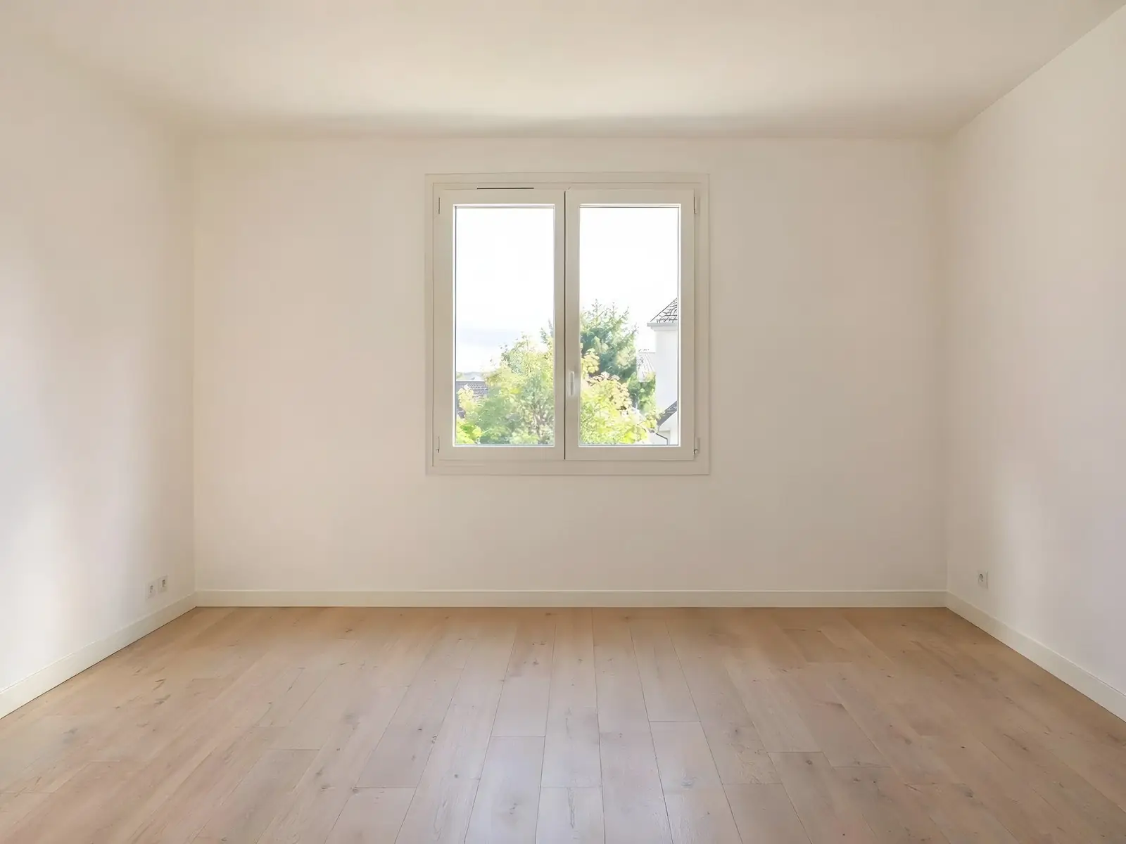 Chambre vide aux murs et au plafond blanc chaud, fenêtre à deux vantaux au fond, parquet clair, plinthes blanches