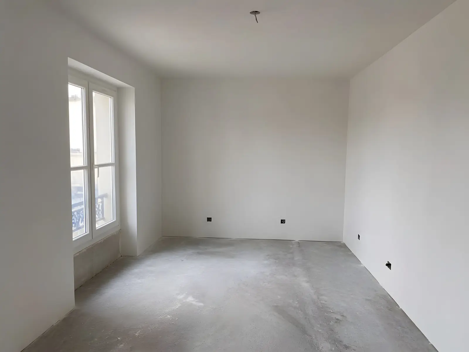 La même pièce aux murs et au plafond d’un blanc uni, plus aucune bande visible, sol encore brut