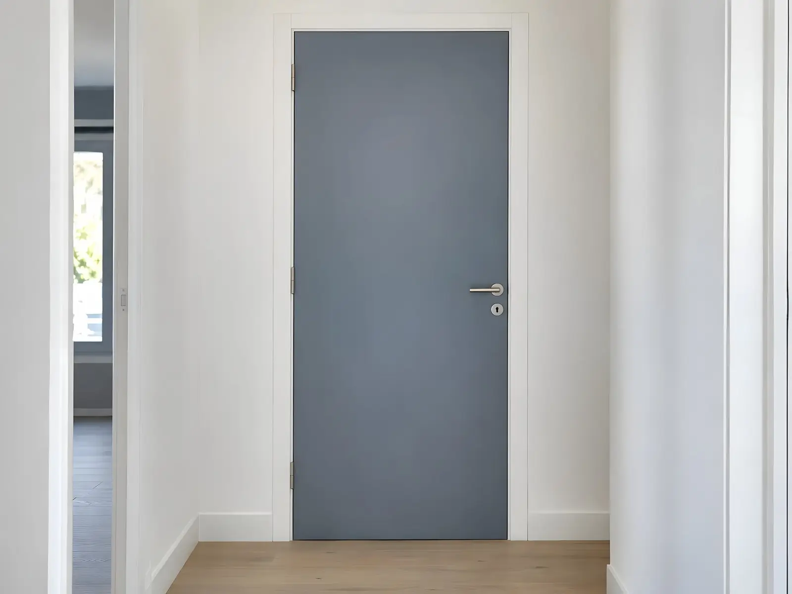 Porte de couloir laquée bleu-gris satiné, encadrement et plinthes blancs, poignée en inox, parquet clair au sol