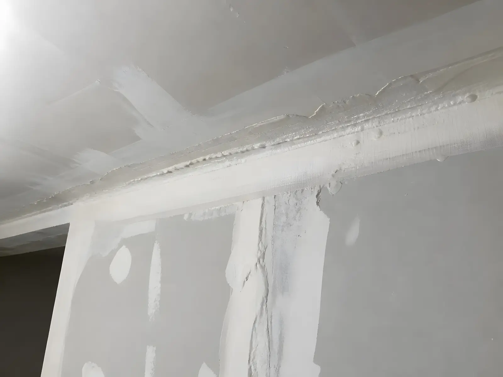 Angle de mur et de plafond en plaques, joints couverts d’une bande épaisse et d’enduit en paquets