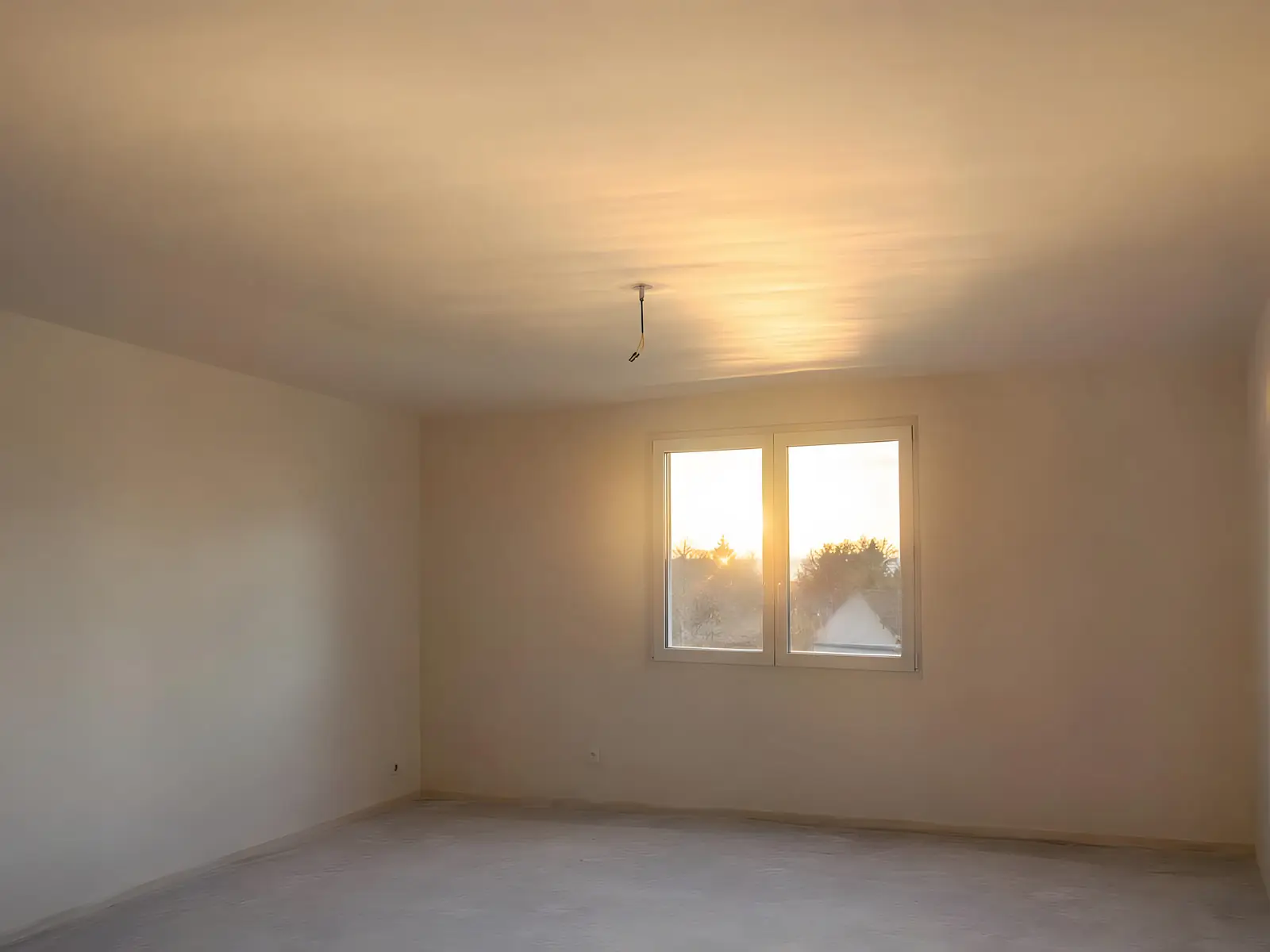 Chambre vide au plafond neuf lisse et uniforme, soleil couchant rasant par la fenêtre, fil du plafonnier au centre