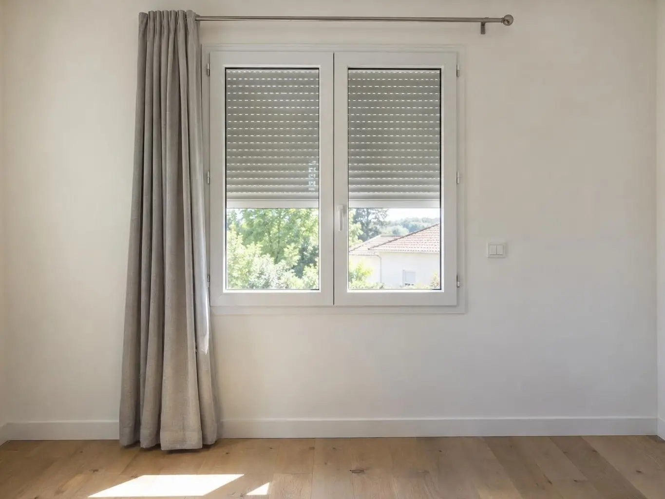 Chambre blanche, fenêtre en PVC à volet roulant mi-descendu, simple interrupteur blanc sur le mur à droite